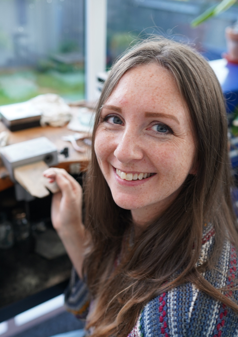 Kate Wainwright Jewellery sitting at her workbench smiling