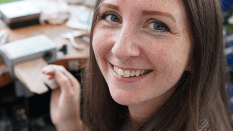 Kate Wainwright Jewellery sitting at her workbench smiling