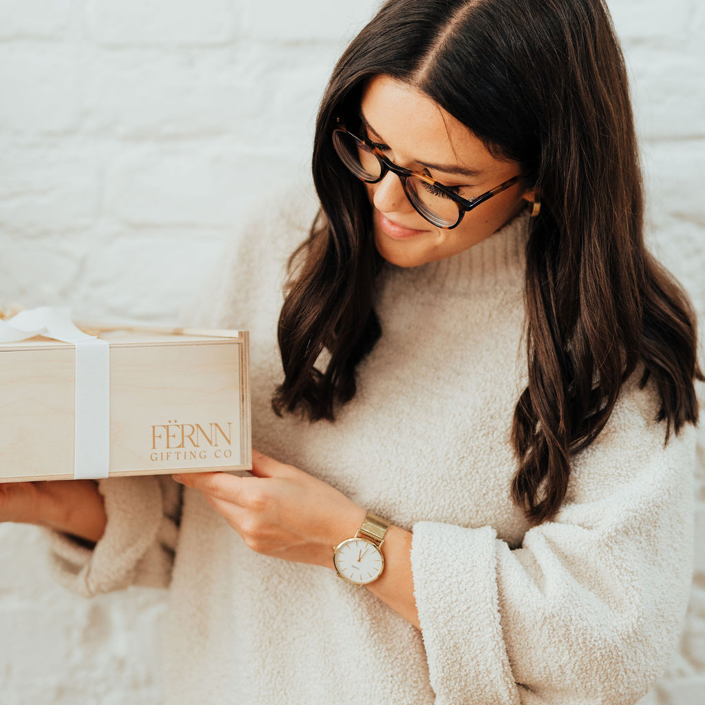 wooden keepsake gift box with white ribbon being tied by a woman's hands