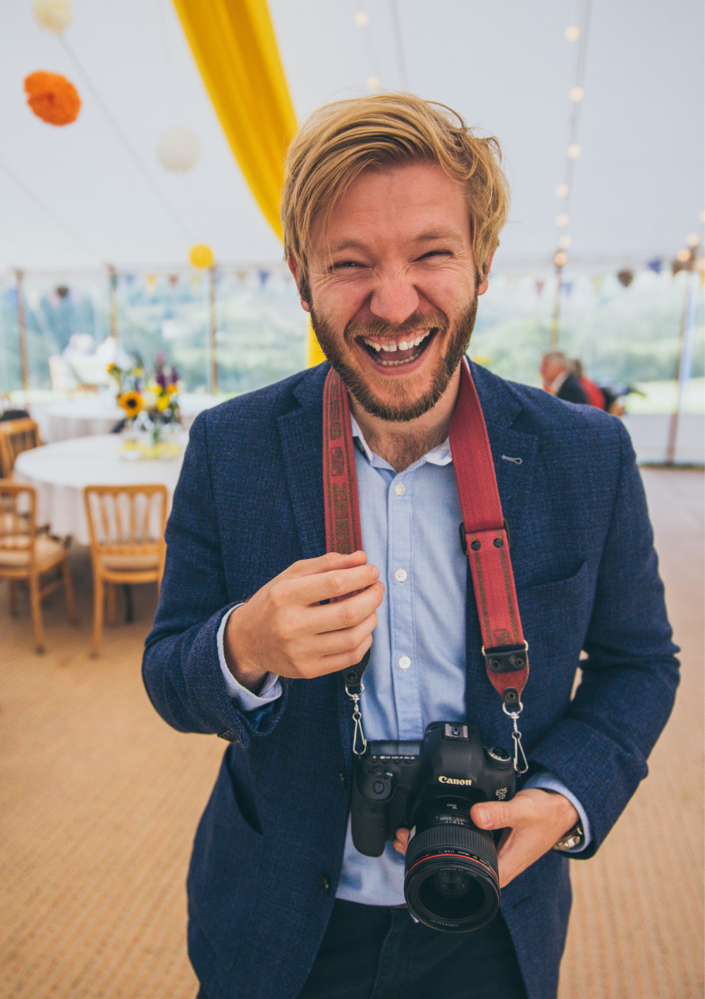 The owner of Shoreline Shaving stood on an empty beach with blue waters and a sunset in the background
