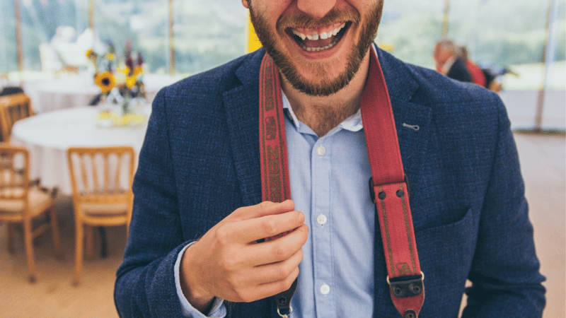 The owner of Shoreline Shaving stood on an empty beach with blue waters and a sunset in the background