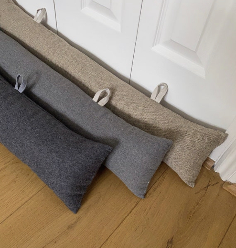 Door Grey draught stoppers with hanging hoops on white door and wooden floor.