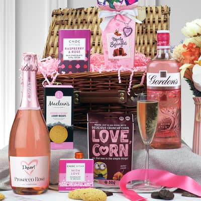 Wicker hamper with pink Prosecco, gin and snacks