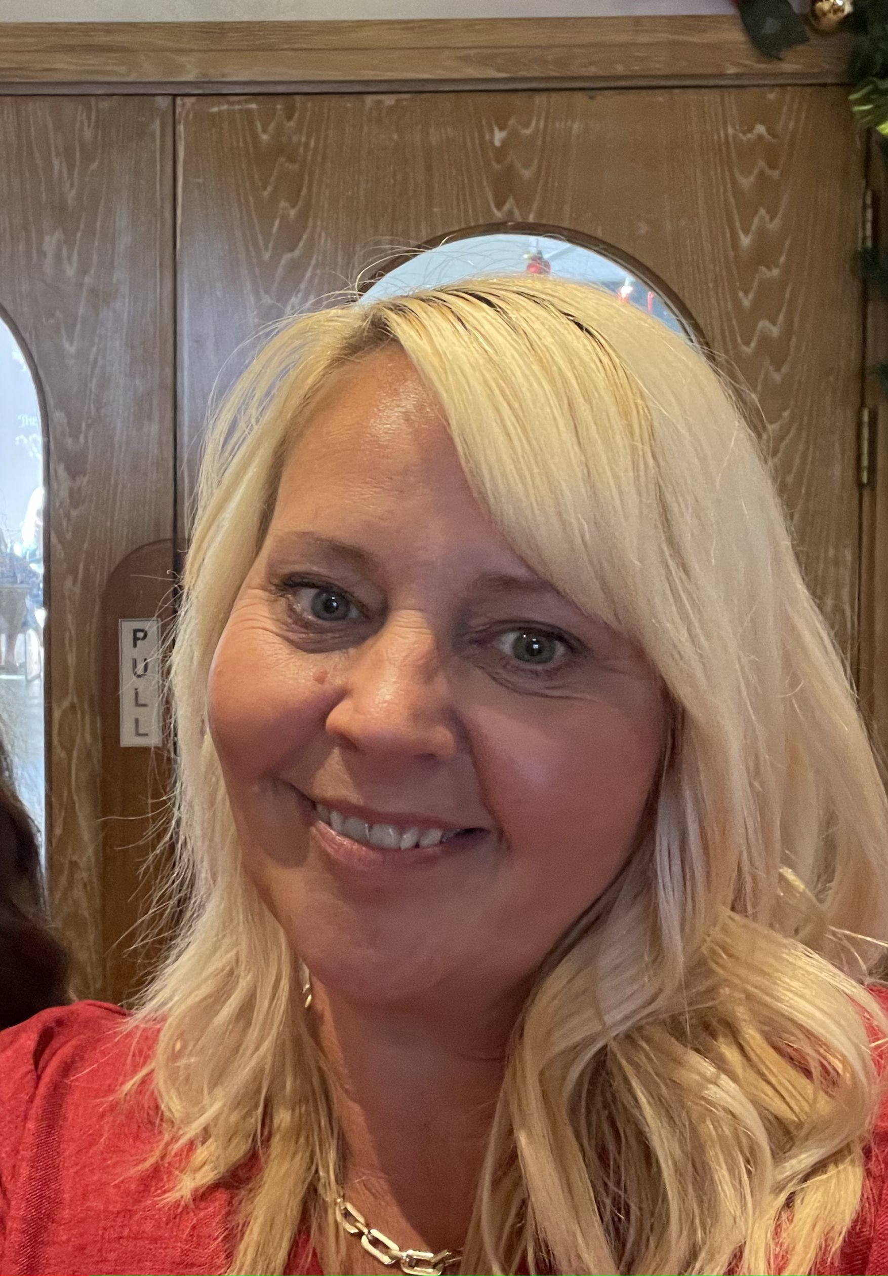 A picture of the owner, smiling. Wearing a black dress with shoulder length blonde hair