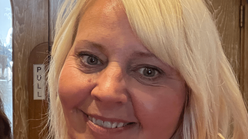 A picture of the owner, smiling. Wearing a black dress with shoulder length blonde hair