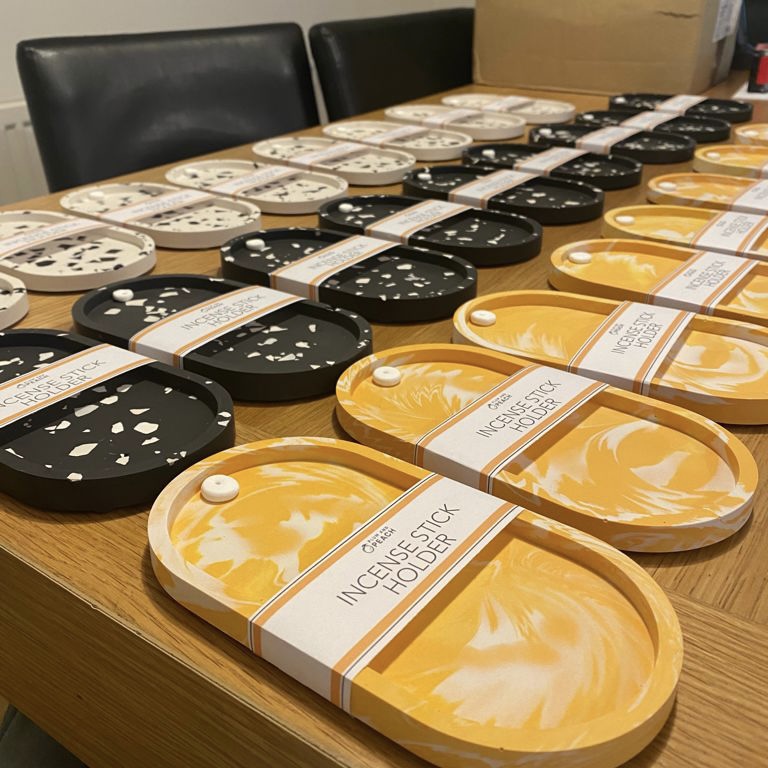 Table full of orange, black and white terrazzo incense holders.