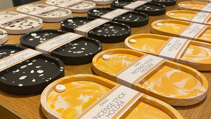 Table full of orange, black and white terrazzo incense holders.