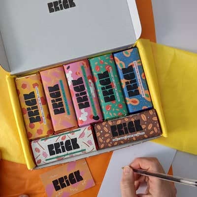 a box of brick chocolate bars with a person writing a gift note from above