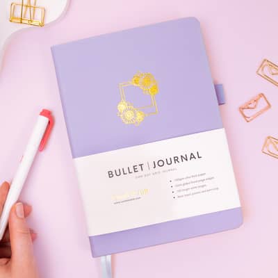 Coral & Ink's purple sunflower bullet journal photographed next to a mild red Zebra Mildliner highlighter pen