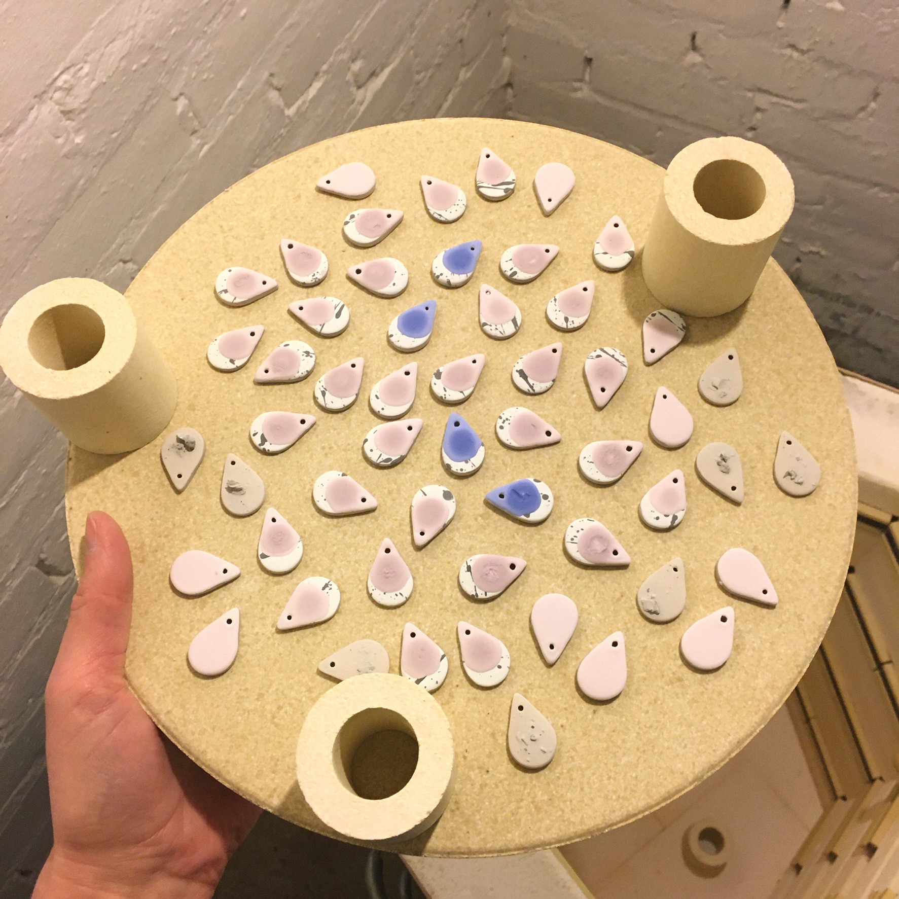 Behind the scenes making ceramic earrings earrings on a kiln shelf