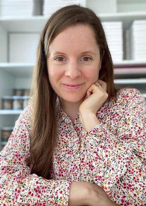 Laura Clempson, the owner of 34th Street is sitting in the studio wearing a floral blouse.