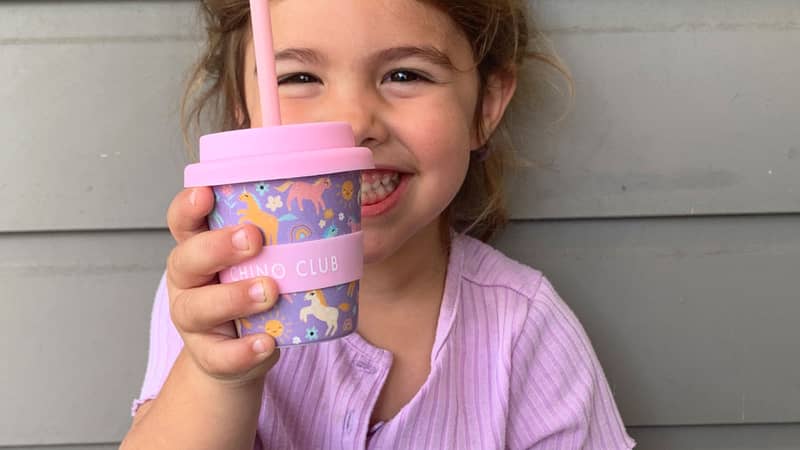 Girl holding unicorn babyccino cup with straw