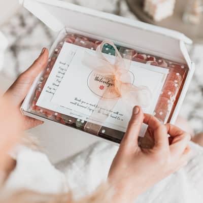 Our signature letterbox open, with a hand pulling on the peach ribbon to reveal the contents inside