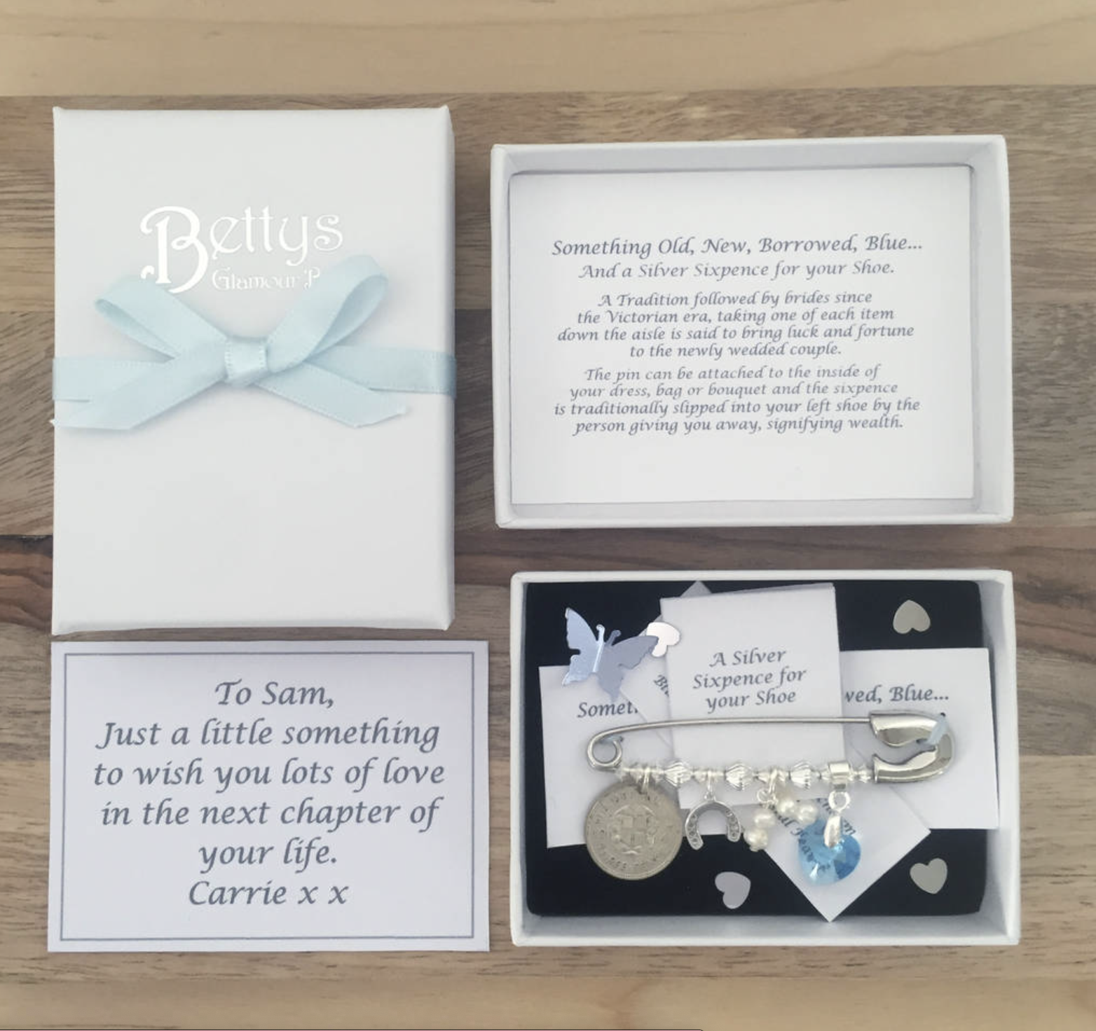 Bridal white gift box with foiled embossed logo of 'bettys glamour box' laying opened with contents showing. Inside is a printed note to the bride & bridal pin