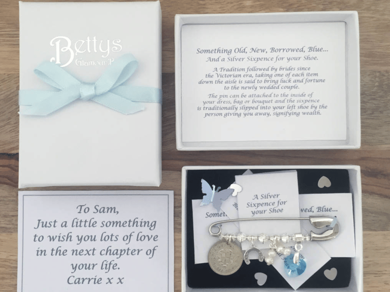 Bridal white gift box with foiled embossed logo of 'bettys glamour box' laying opened with contents showing. Inside is a printed note to the bride & bridal pin