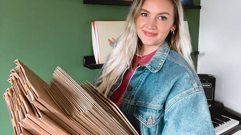 owner, Rachel, of Lune Club holding packages ready to be shipped. Smiling at the camera.