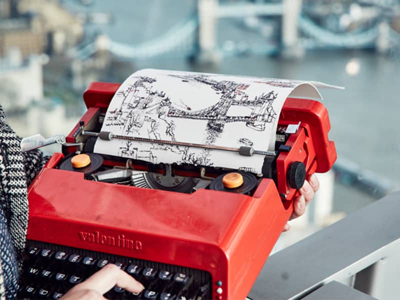 Keira Rathbone typewriter artist typing from life Tower Bridge from the Sky Garden Tower bridge on page and in background finger on key red Olivetti Valentine