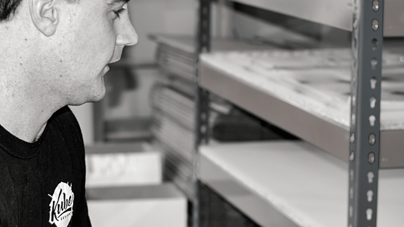 Darryl working at a computer with acrylic stored in background