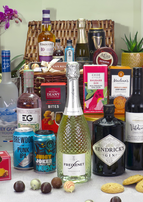 Wicker hamper surrounded by bottles of wine, beer, gin and various snacks