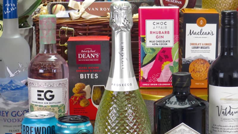 Wicker hamper surrounded by bottles of wine, beer, gin and various snacks