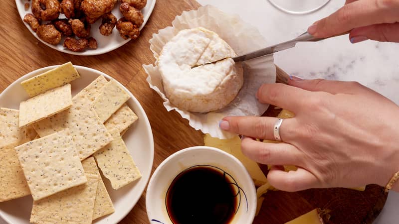 Amazing cheese and crackers board cutting into cheese with a glass of wine