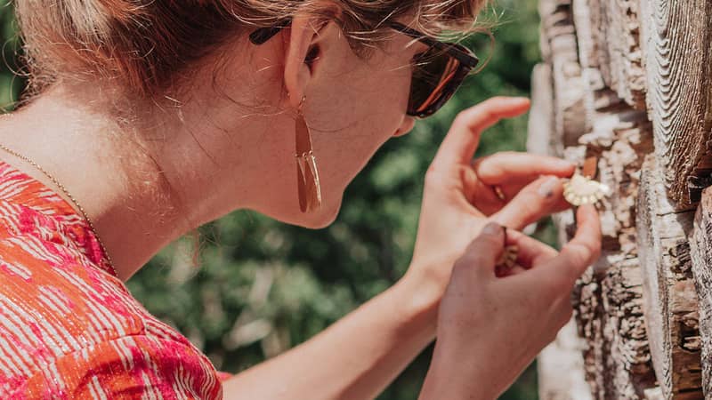 Nic behind the scenes on a photoshoot styling a pair of wood and hand beaten brass earrings in a textured wood stack.