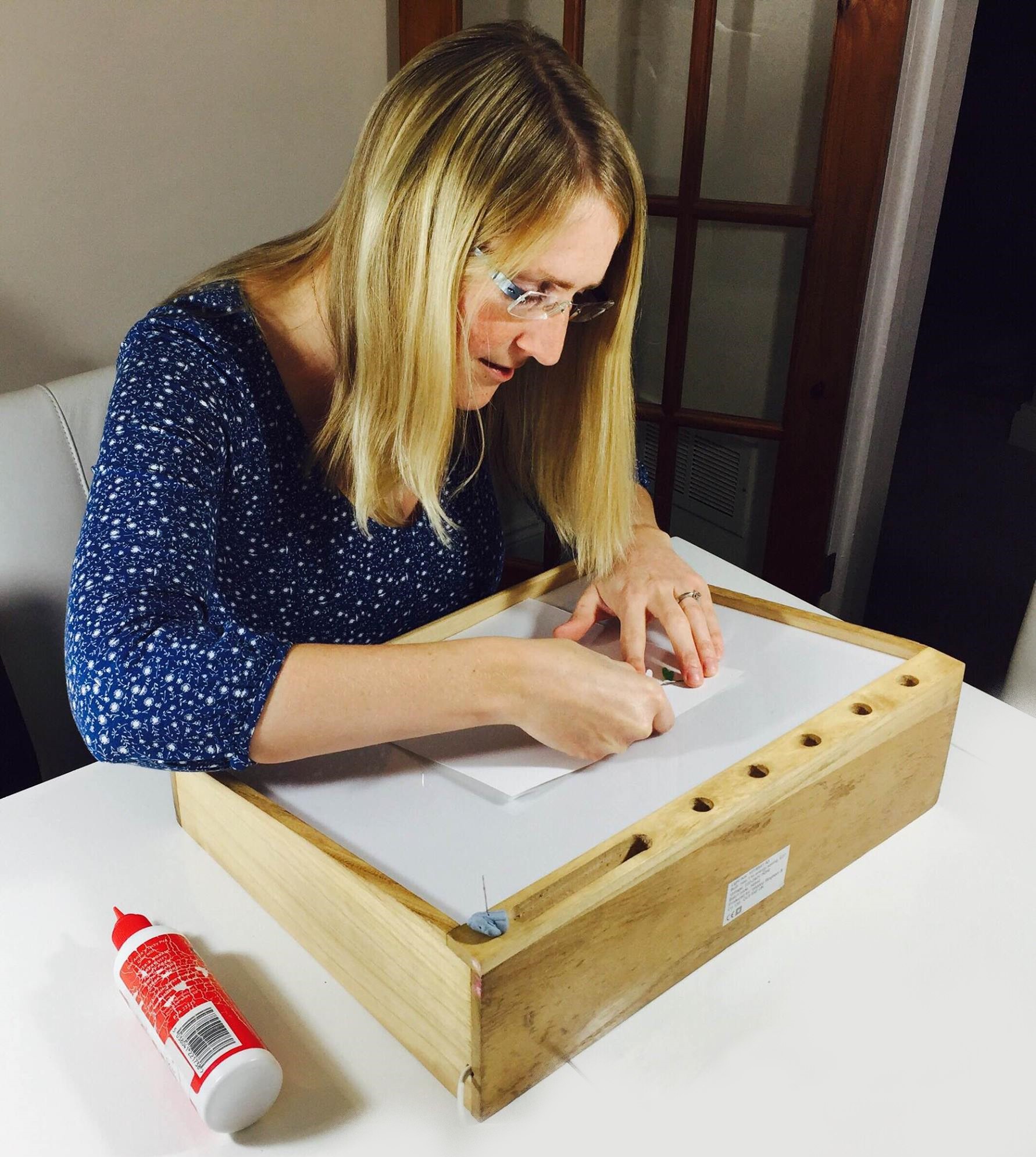 Erika gluing dragonflies onto the backing paper