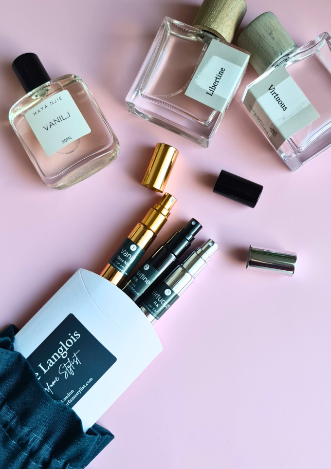 ILK Perfumes and Maya Njie 50ml bottles of fragrances and refillable travel sprays arranged on a soft pink background, showcasing a curated fragrance gift set