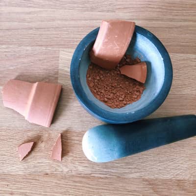 Crush terracotta pot in a mortar and pestle