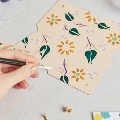 Hand painting a floral design on leather
