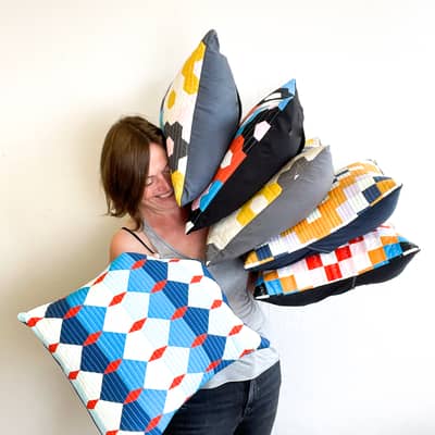 quilted hexagon cushion held up in front of Lucy Engels