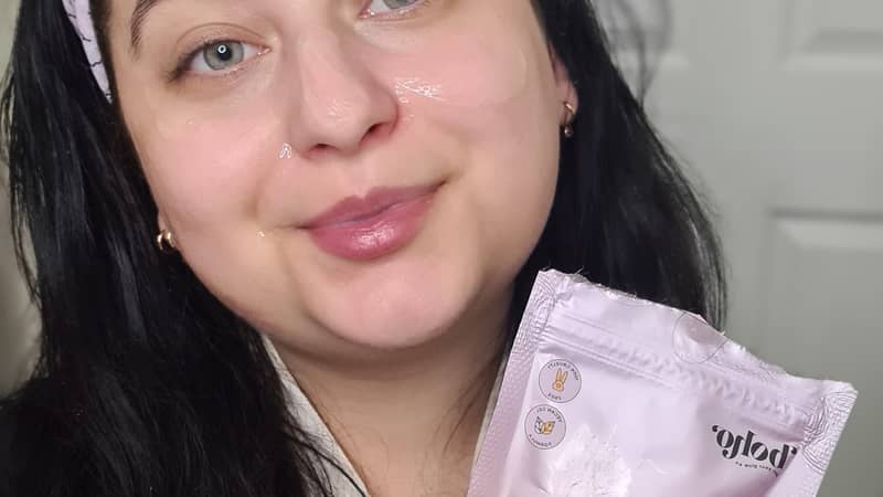 a lady with black hair and pink head band holding a pink pouch that contains face mask