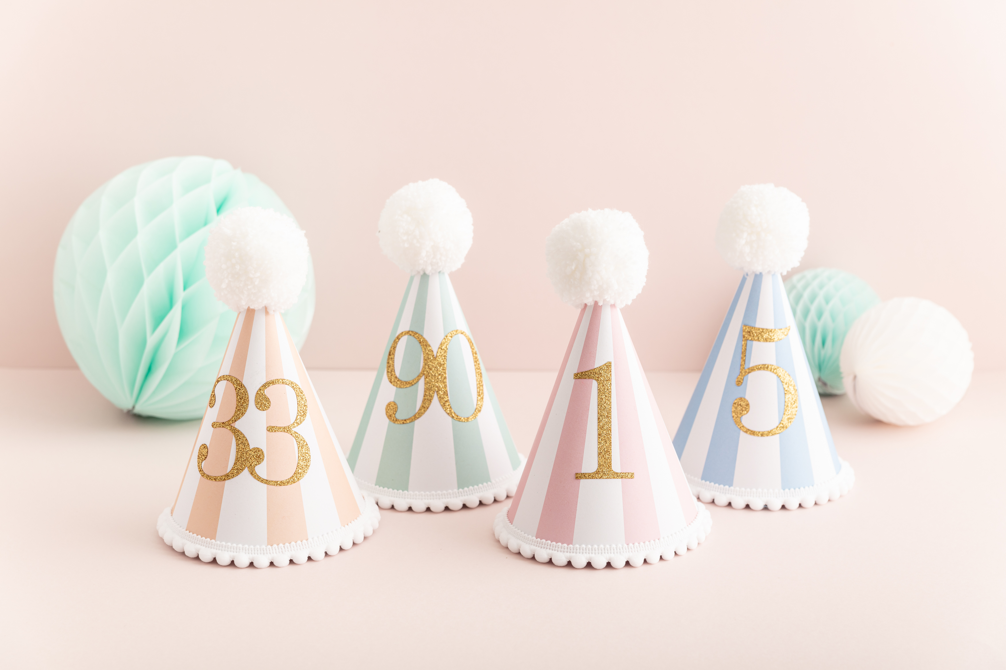 Handmade striped party hats with a pom pom and trim and a gold glittery number