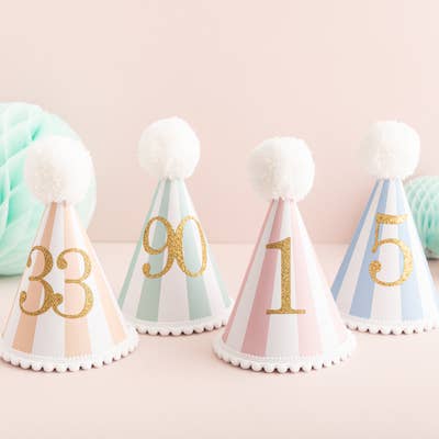 Handmade striped party hats with a pom pom and trim and a gold glittery number