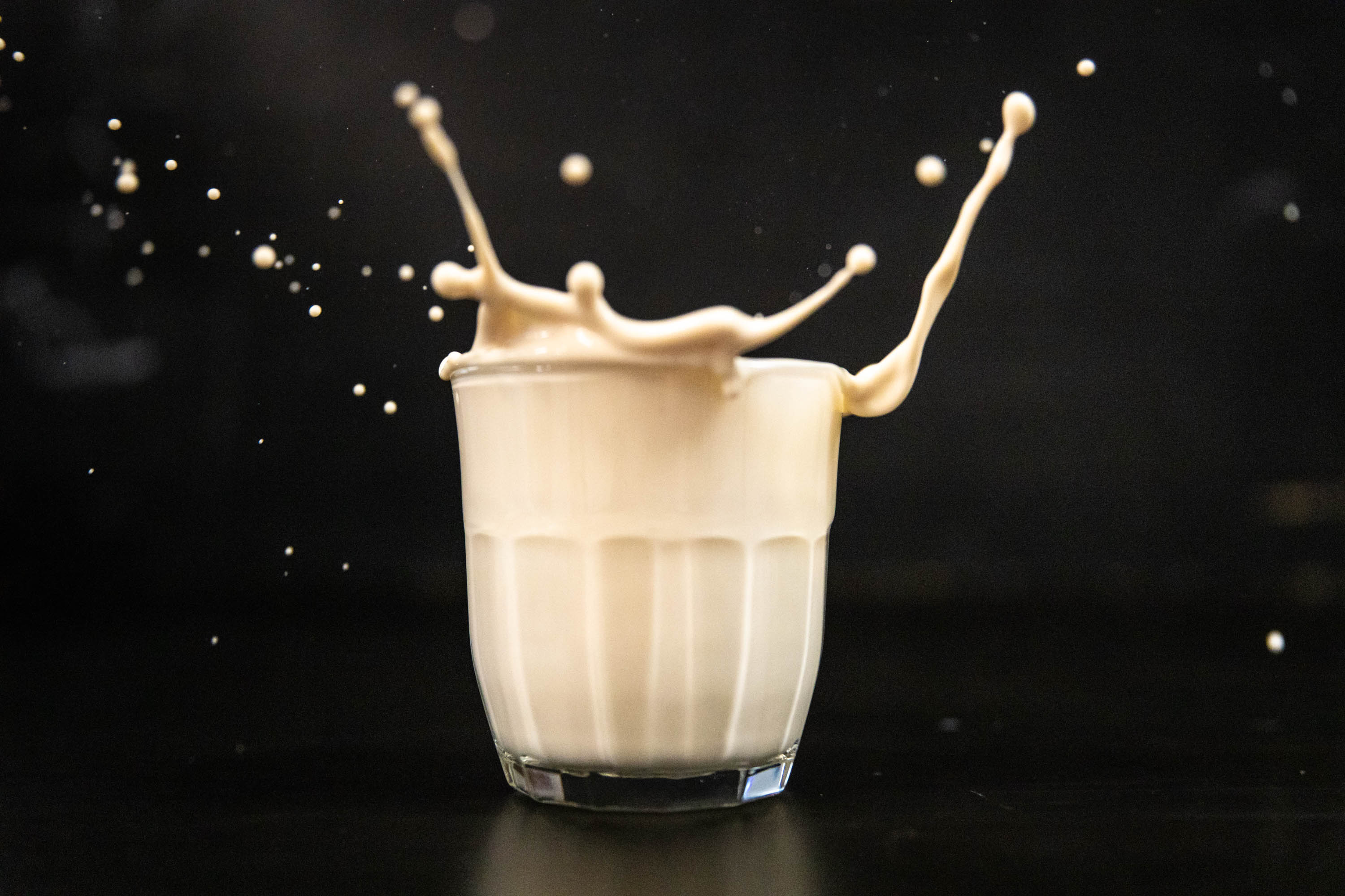 Glass of eggnog with eggnog spilling out of the top