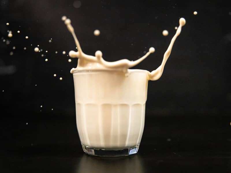 Glass of eggnog with eggnog spilling out of the top