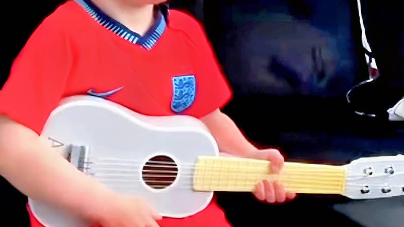 Young child singing and playing guitar while listening to personalised music with his name and birthday in the lyrics, created by My First Music