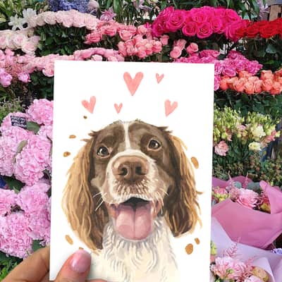 Our Licks and Kisses Spaniel Card for Valentines and Anniversaries, held up in front of a flower display