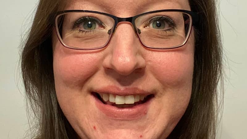 A picture of Hayley owner of Hayleys Mosaics. She has brown hair and blue eyes with glasses and an orange shirt