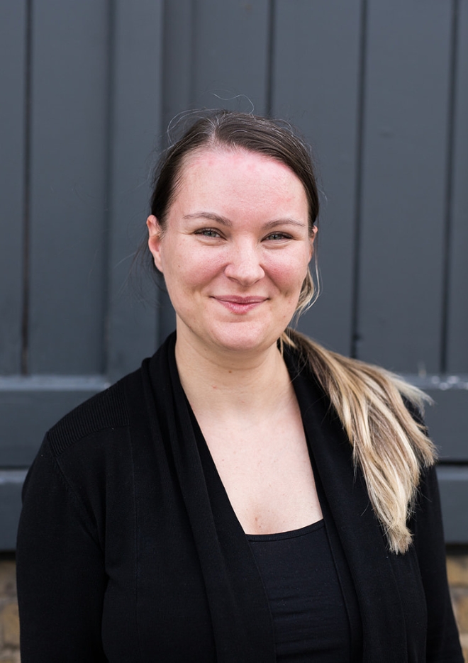 Founder of Journeys Made, Jade Scammells, a white British female with green eyes and dark brown hair smiling, wearing a black top and black cardigan