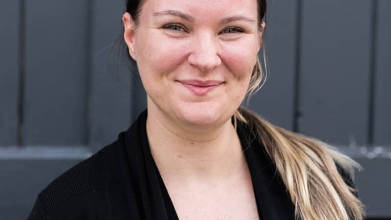 Founder of Journeys Made, Jade Scammells, a white British female with green eyes and dark brown hair smiling, wearing a black top and black cardigan