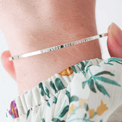 model wears slim silver bangle with words be good to yourself engraved
