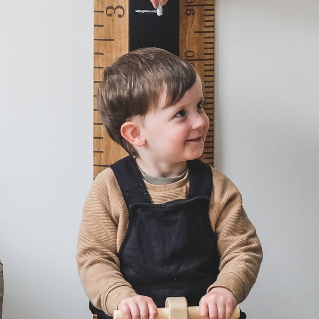 Hendrick measuring up against wooden height chart