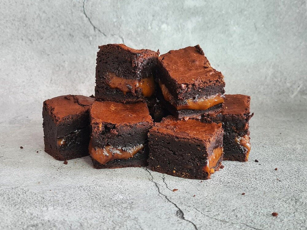 A stack of chocolate brownies filled with a thick layer of salted caramel