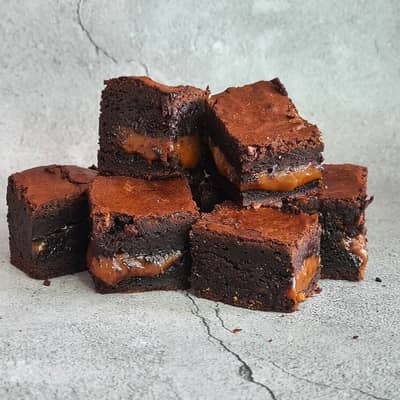 A stack of chocolate brownies filled with a thick layer of salted caramel
