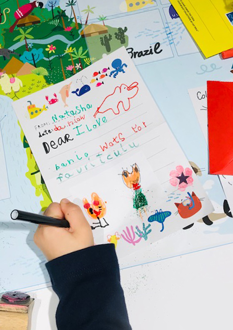 Child writing a reply and drawing a picture in response to Banjo's letter.