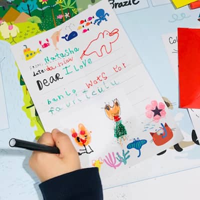 Child writing a reply and drawing a picture in response to Banjo's letter.