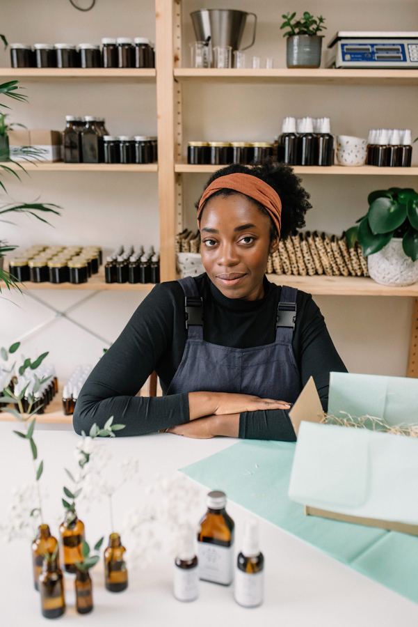 Founder Ibi sitting at her work desk in front of product shelves