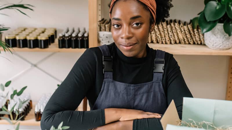 Founder Ibi sitting at her work desk in front of product shelves