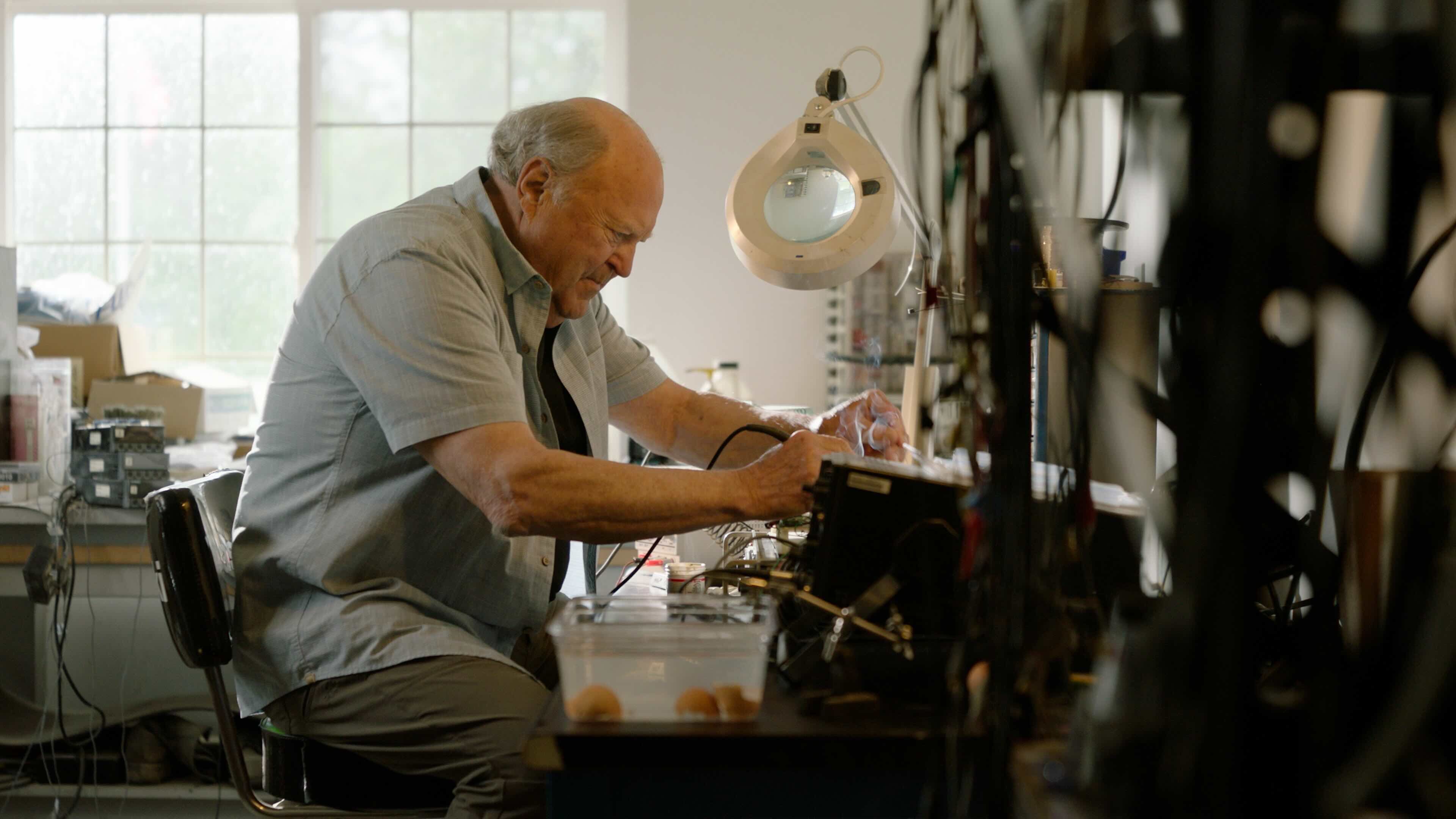 John Adams working at his workbench in his home workshop, testing electronic components used in his early IVL experiments
